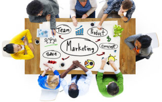 Ein Team, das um einen Tisch herum sitzt und eine Marketingstrategie entwirft aus der Vogelperspektive.