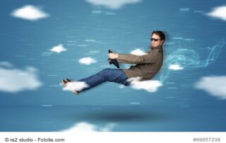 Ein Mann mit Sonnenbrille, der, wie in einem Auto sitzend, durch das Bild fliegt.