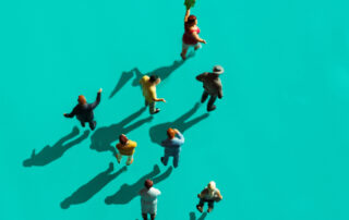 Acht Figuren, die zu einer losen angeordnet sind und von oben fotografiert wurden: Eine Figur führt die Gruppe voran.