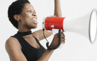 Frau mit schwarzem Top ruft in ein Megaphon
