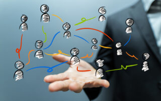 Gezeigt werden mehrere Strichmännchen, die mit farbigen Linien miteinander verbunden sind. Sie symbolisieren das systemische Denken.